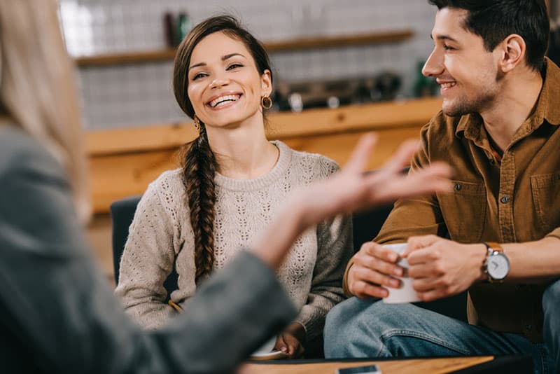 lächelndes Paar im Gespräch mit Freund