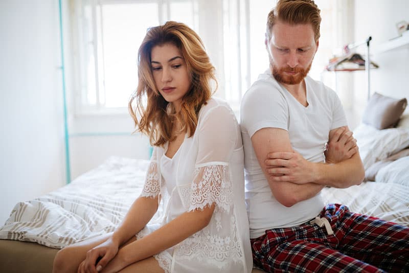 unglückliches Paar sitzt auf dem Bett