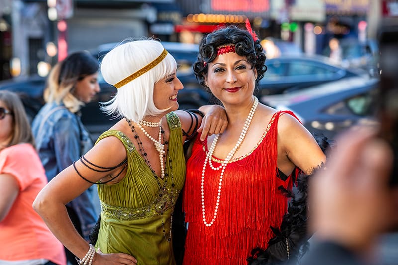 Zwei Frauen mittleren Alters tragen ein Flapper-Kostüm, während sie für die Fotografie posieren