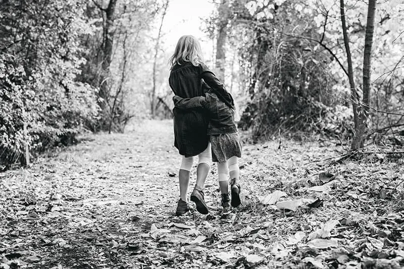 zwei Kinder umarmen sich beim Gehen im Wald