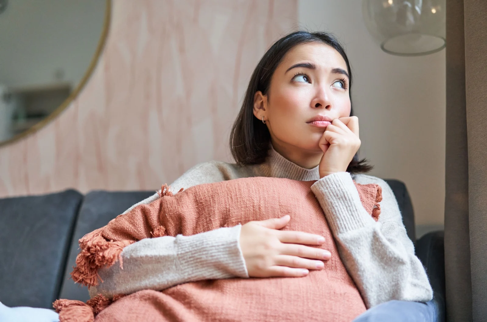 Asiatische Frau denkt auf der Couch