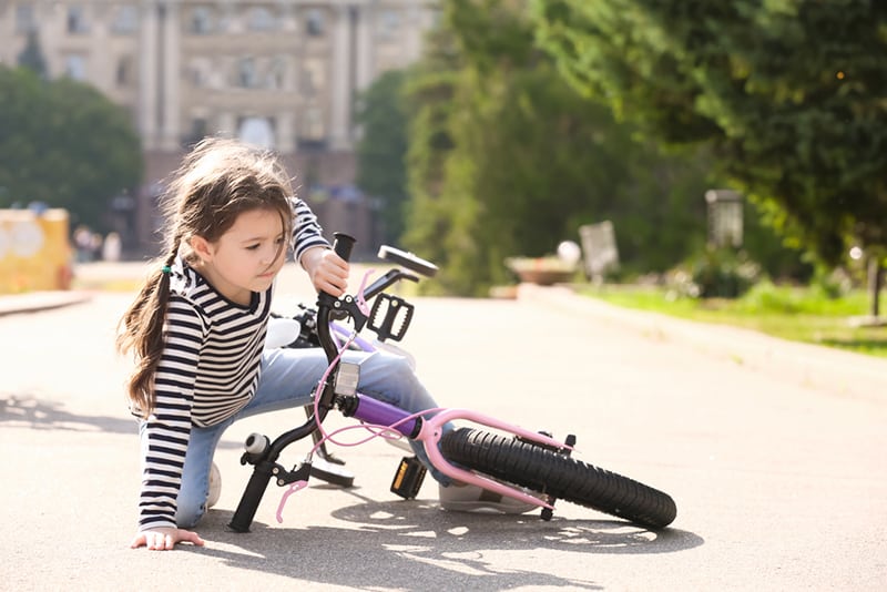 Das süße kleine Mädchen ist unterwegs von ihrem Fahrrad gefallen
