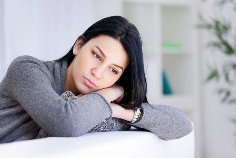Einsame traurige Frau tief in Gedanken auf der Couch gelehnt