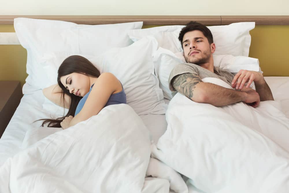 Der tätowierte Mann lügt und sieht die schlafende Frau besorgt an