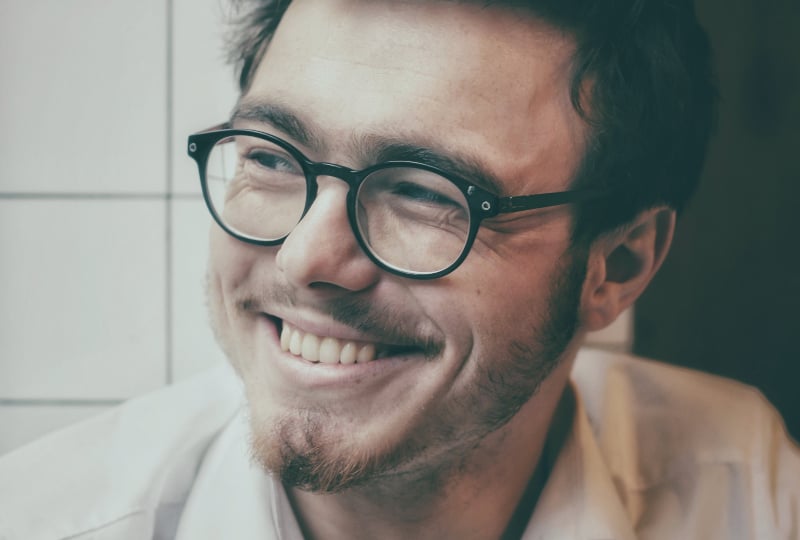 Ein Mann mit Bart und Brille lacht