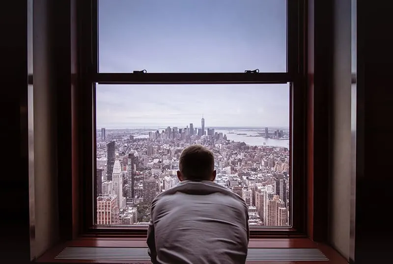 Ein Mann stand allein in der Nähe des Fensters mit Blick auf die Stadt