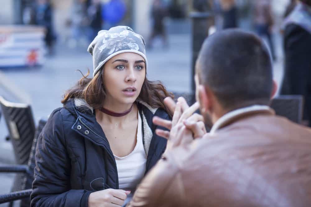 Ein Mann und eine Frau sitzen und streiten sich auf der Terrasse eines Cafés