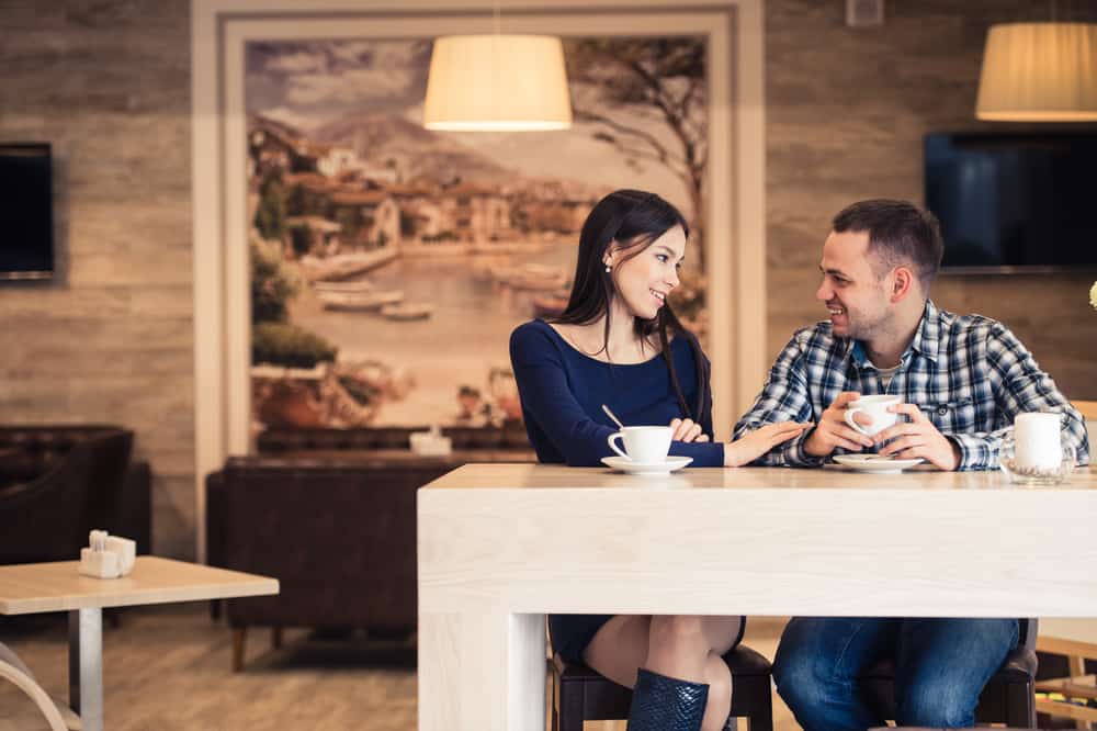Ein lächelnder Mann sitzt mit seiner Frau in einem Café