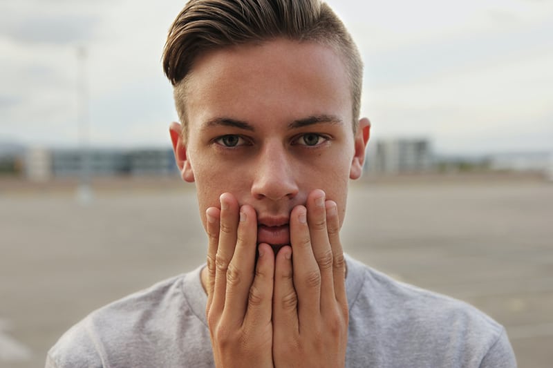 Ein nervöser Mann berührt das Gesicht, während er alleine steht