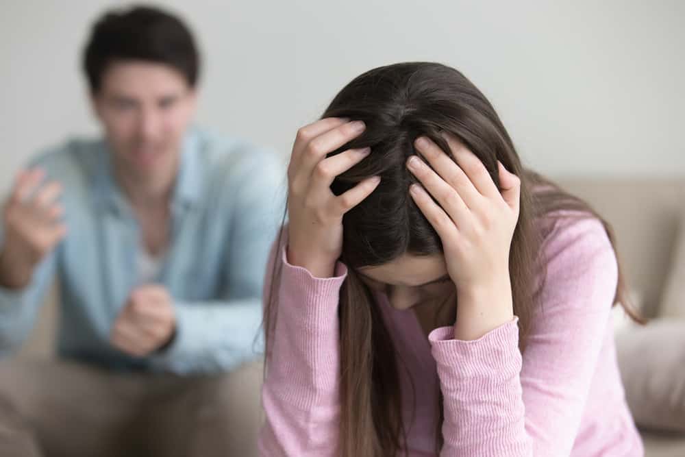 Ein trauriges Mädchen hält ihren Kopf, während ihr Mann sie geistig missbraucht