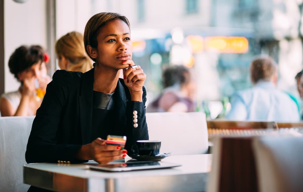 Eine besorgte Frau mit einem Handy in der Hand sitzt in einem Café