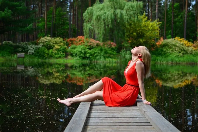 Eine hübsche Frau in einem roten Kleid sitzt auf dem Pier