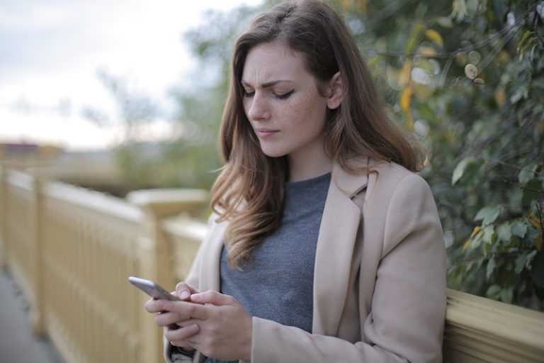 eine verwirrte Frau mit ihrem Smartphone