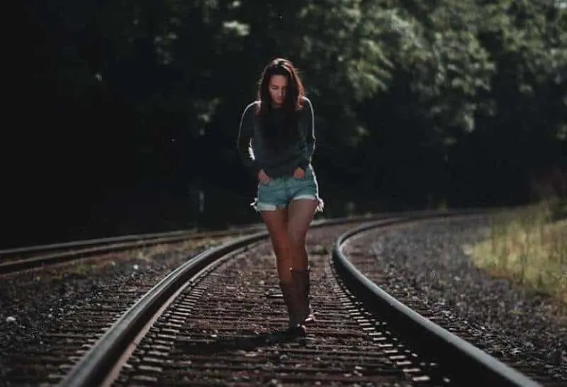 ein Mädchen, das die Eisenbahnschienen entlang geht