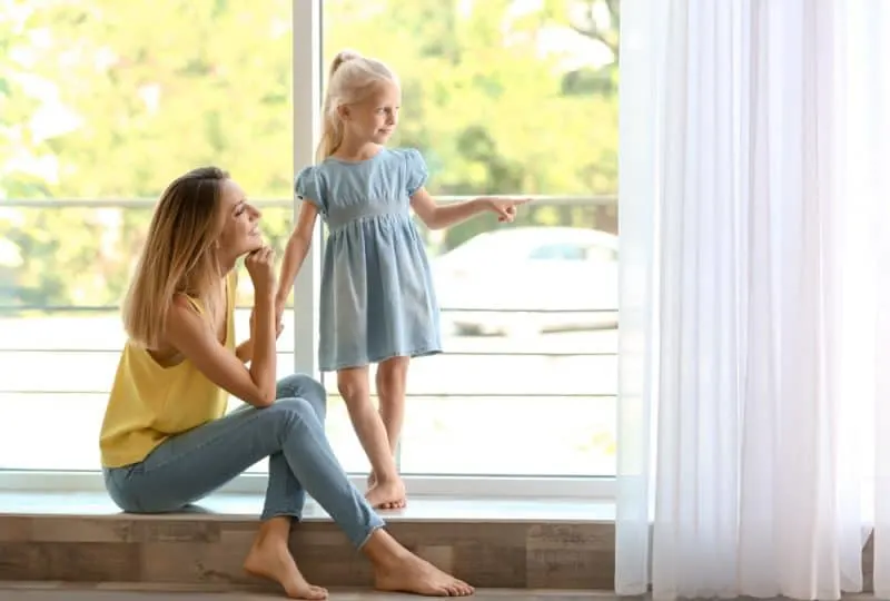 Eine junge Mutter mit ihrer Tochter schaut aus dem Fenster