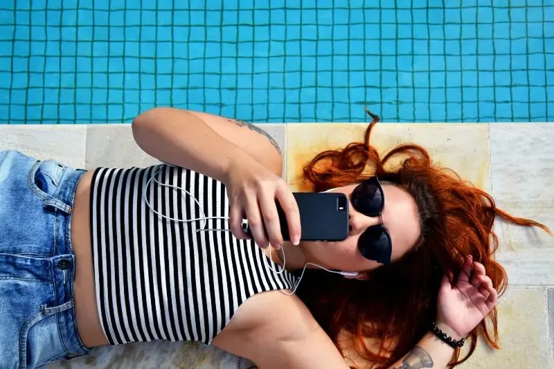 Frau schreibt am Pool eine SMS