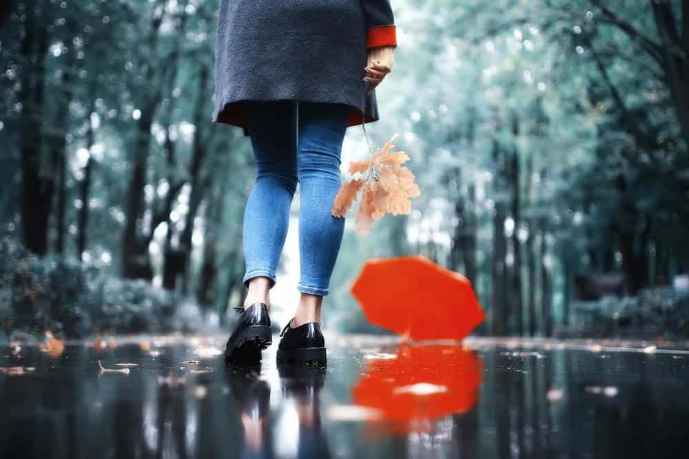 Konzentrieren Sie die Beine eines Mädchens in Schuhen, die im Regen laufen