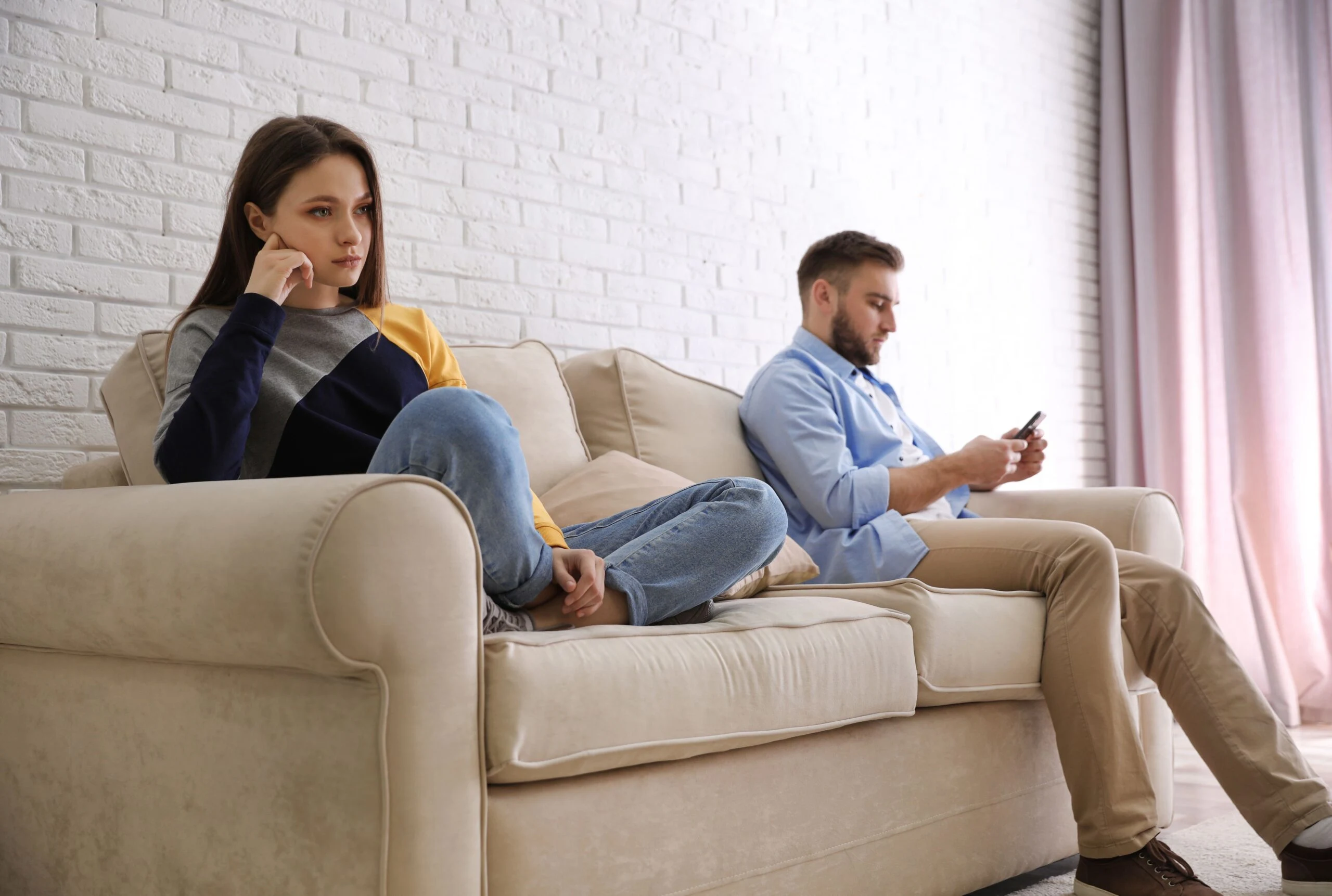 Mann haelt ein Telefon und ignoriert eine Frau