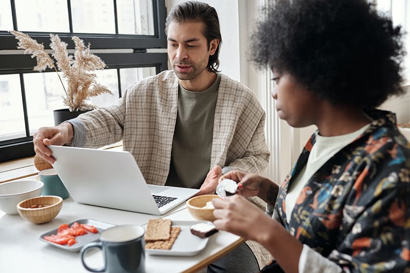 Mann mit Laptop beim Frühstück mit einer Freundin