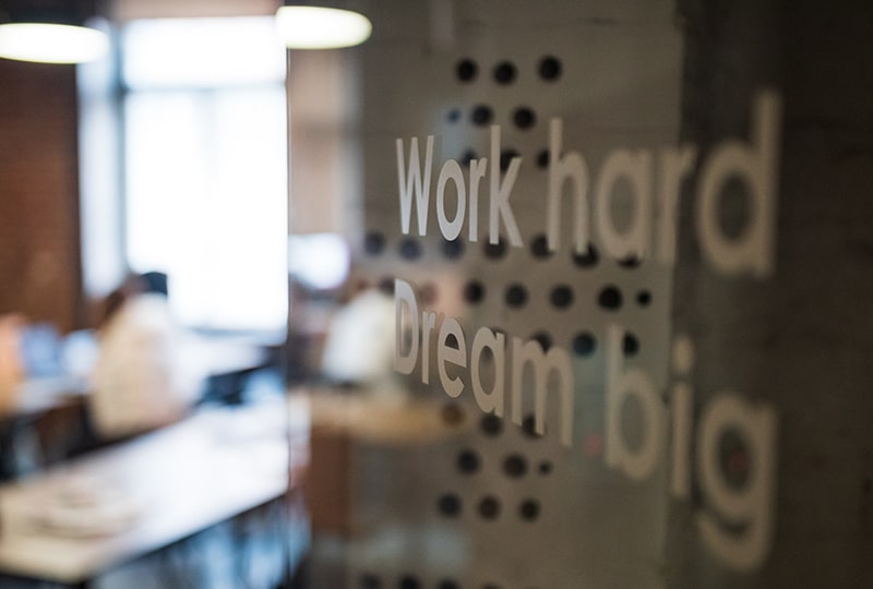 "Arbeite hart, träume groß" Text auf klarer Glaswand