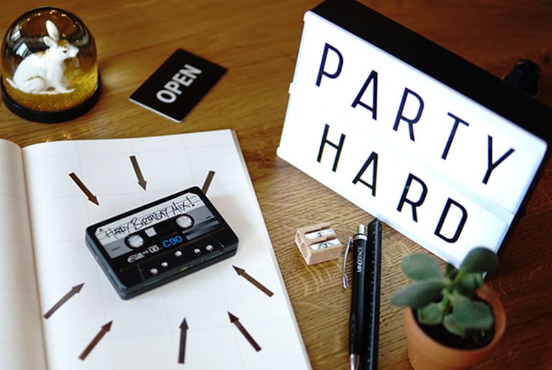 Tonband auf Notebook und Leuchtkasten daneben mit der Meldung "Party hard"