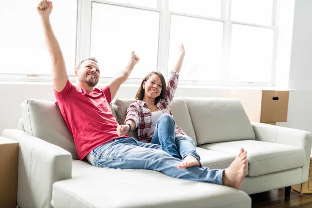 ein glückliches Paar sitzt auf einer Couch in einer neuen Wohnung