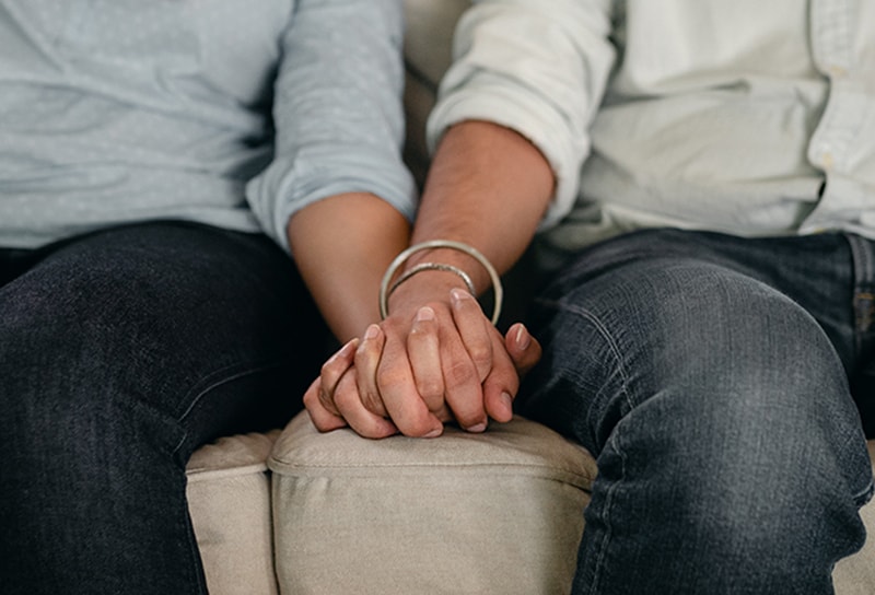 ein liebendes Paar, das Hände hält, während es auf der Couch sitzt