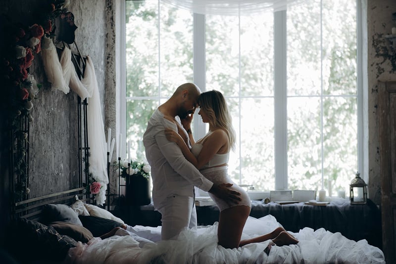 Ein liebevolles Paar, das in einem Moment der Intimität auf dem Bett kniet
