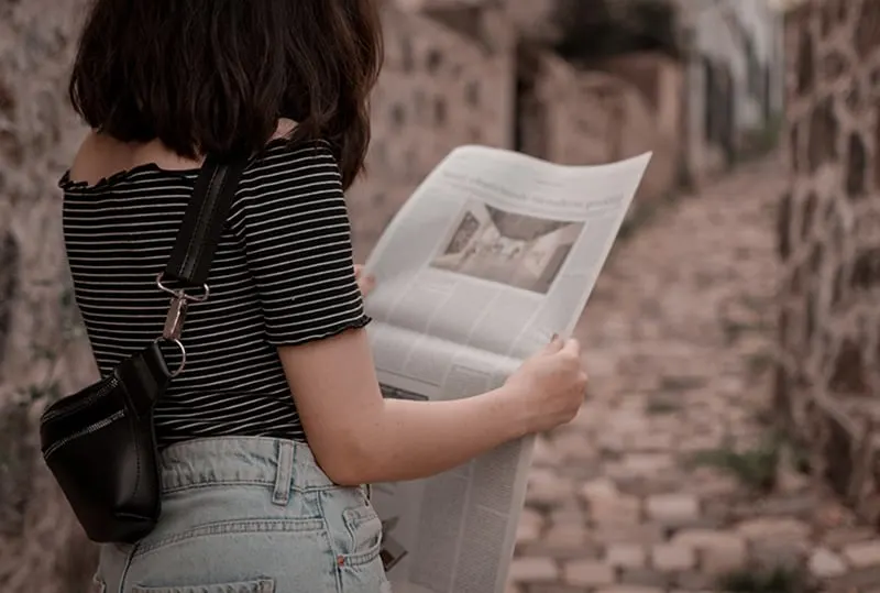eine Frau, die Zeitung liest, während sie auf der Straße steht