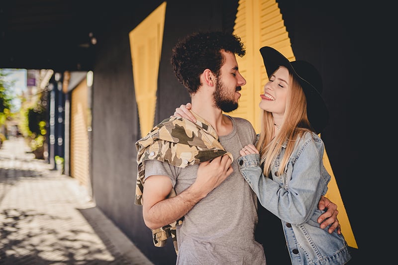 Eine Frau zeigt einem Mann ihre Zunge, während sie sich umarmt