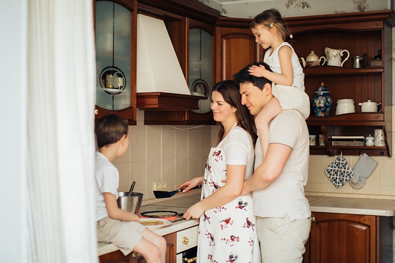 eine Frau, die mit ihrem Mann und ihren Kindern in der Küche kocht