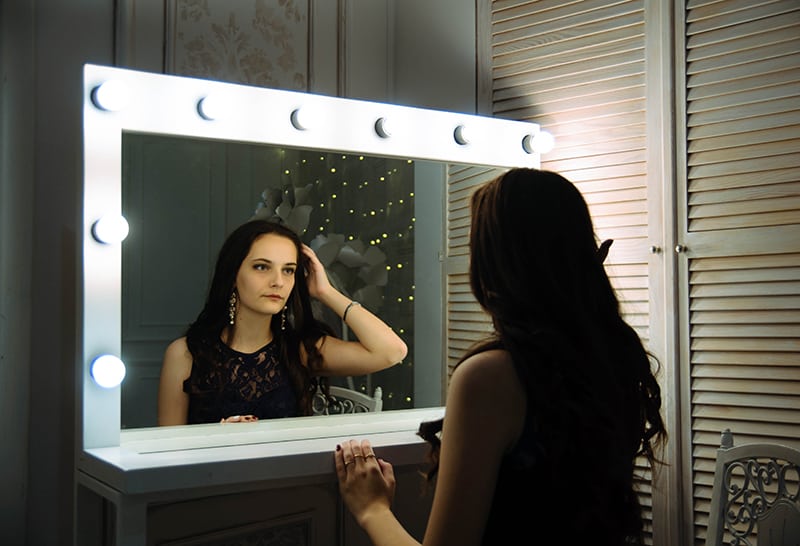 eine Frau, die sich in den Spiegel schaut und ihre Haare berührt