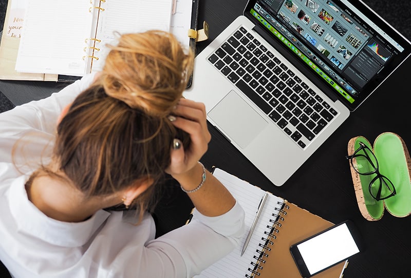 Eine Frau, die sich stressig fühlt, sitzt am Schreibtisch im Büro