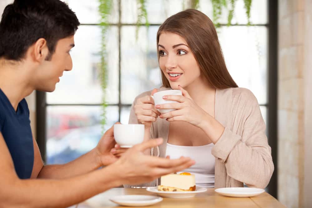 eine Frau, die überrascht aussah und einen Mann ansah, während sie eine Tasse Kaffee hielt