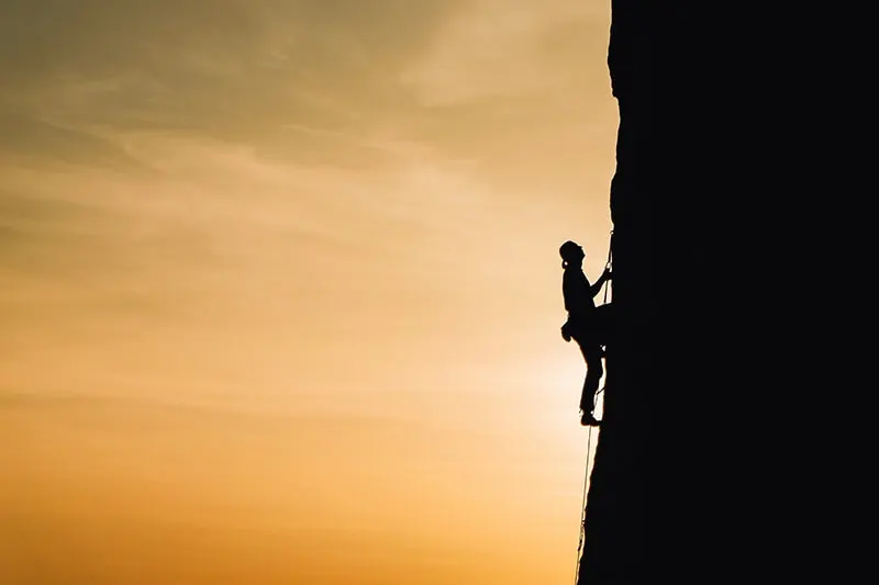 eine Person, die während des Sonnenuntergangs auf den Felsen klettert