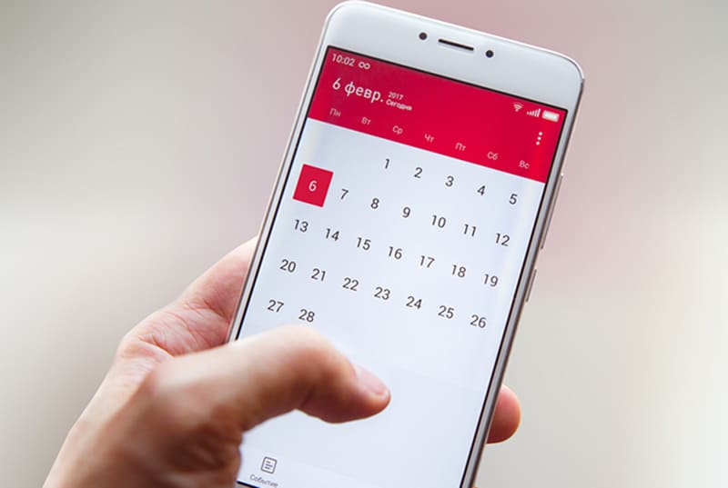 eine Person, die ein Smartphone hält und einen Kalender verwendet
