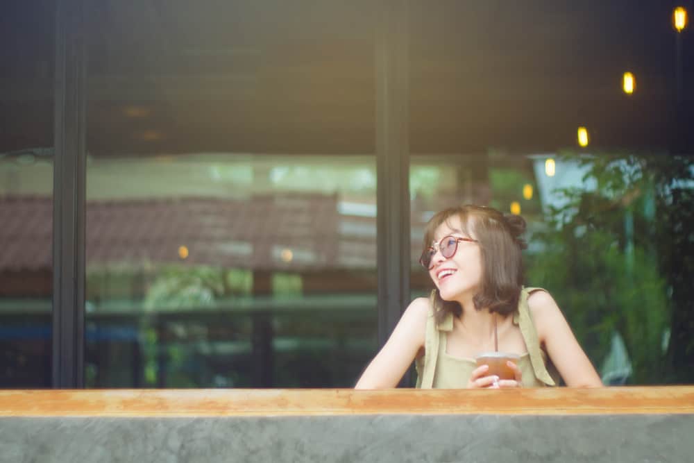 eine asiatische Frau mit Brille mit einem Lächeln denkt nach