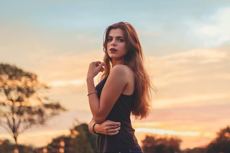 eine hübsche Frau, die draußen bei Sonnenuntergang steht