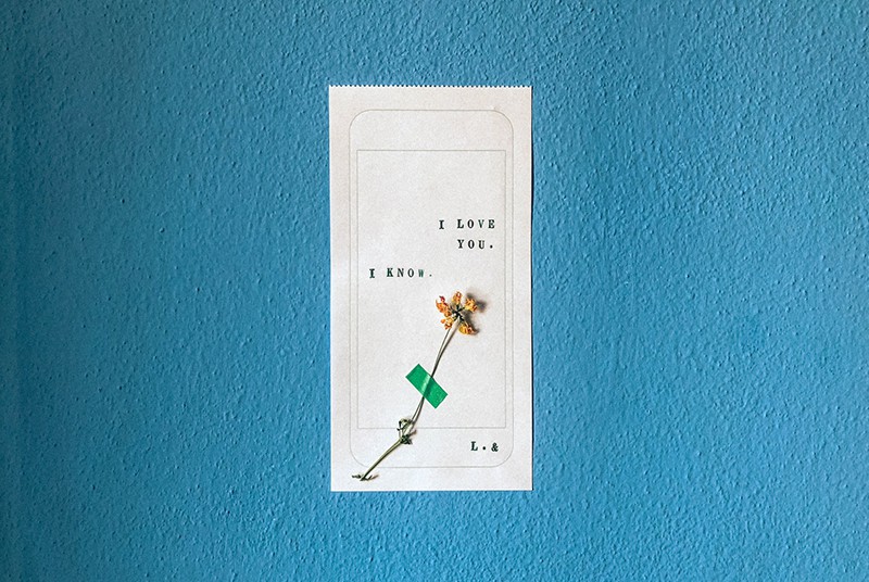 eine kurze Liebeserklärung auf weißem Papier mit einer Blume darauf