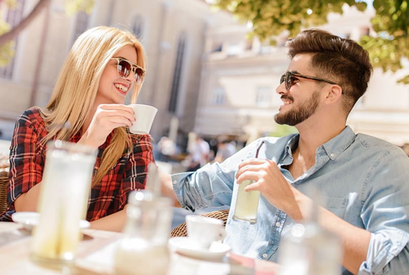 eine lächelnde Frau und ein lächelnder Mann, die an einem Date im Café sitzen