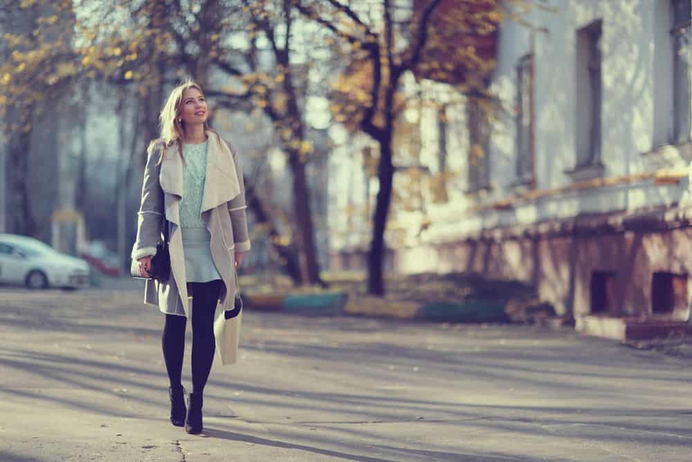 eine lächelnde Geschäftsfrau, die im Herbst die Straße entlang erntet