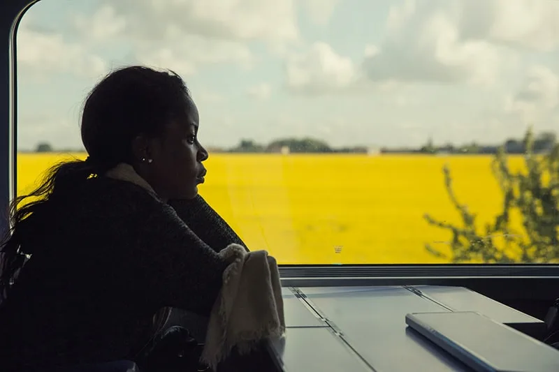 eine nachdenkliche Frau, die alleine im Zug sitzt