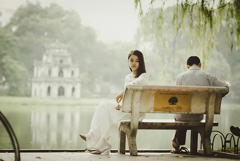 eine traurige Frau, die auf der Bank neben einem Mann in der Nähe des Sees sitzt