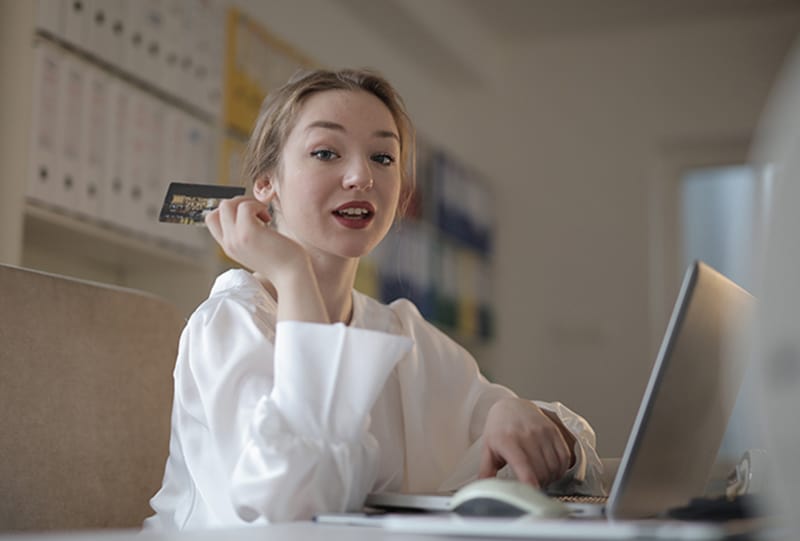 junge Frau hält eine Kreditkarte beim Online-Bezahlen