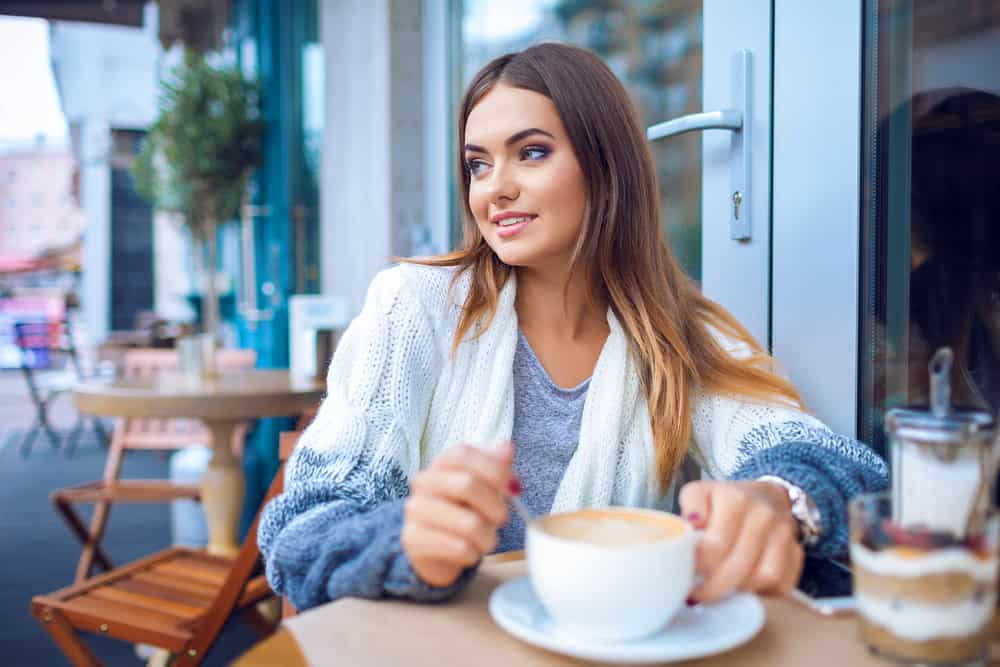 junges attraktives Mädchen, das Kaffee in einem Café trinkt