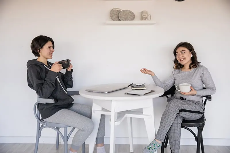 zwei Frauen unterhalten sich, während sie gemeinsam am Tisch Kaffee trinken