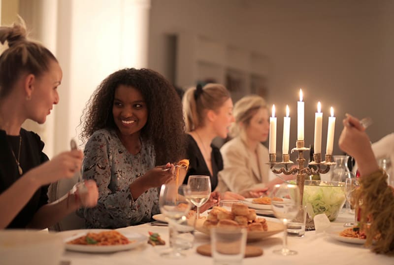 zwei Frauen unterhalten sich während des Abendessens, während sie nebeneinander sitzen