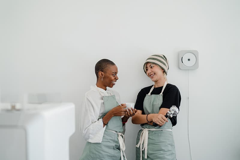 zwei lächelnde Frauen, die bei der Arbeit miteinander sprechen