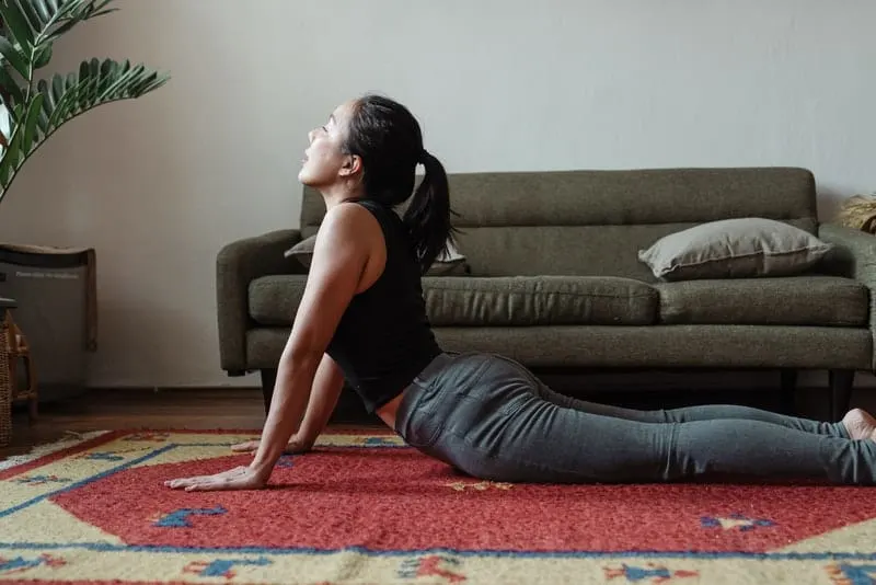 Auf dem Boden im Raum führt eine Frau eine Yoga-Übung durch