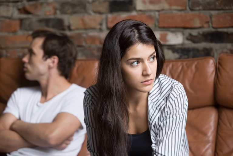 eine traurige Frau, die beiseite schaut, während sie neben einem Mann sitzt und sie ignoriert